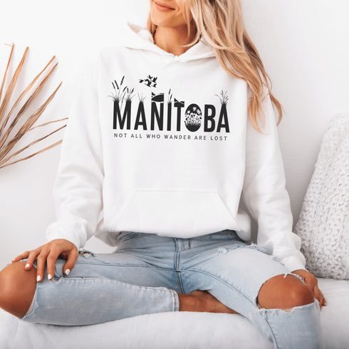 Featuring a serene prairie landscape, the design captures the essence of the heartland with wildflowers and prairie grasses growing out of the letters Manitoba.